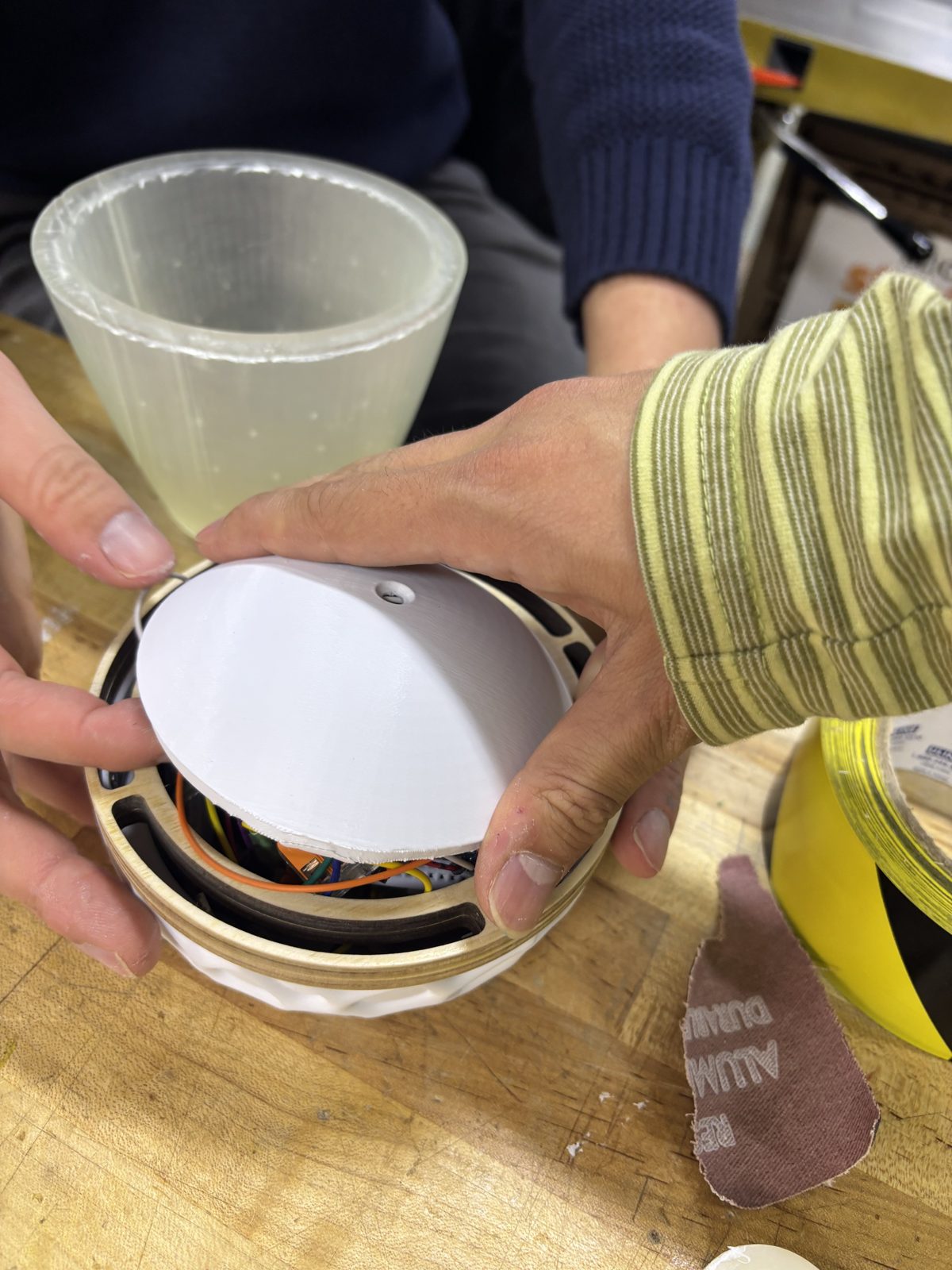 Hands fitting the 3D-printed lid onto the plywood band during assembly